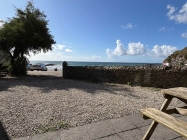 Sea view in the background with pebbles and wall in foreground