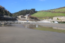 Looking across wet sand inland to Boat House from the shoreline