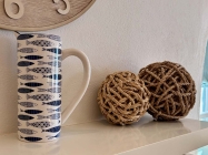 Wall shelf with a tall jug with a fish pattern on it and decorative woven rattan balls 